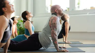 women and man with tattoos doing yoga in studio 