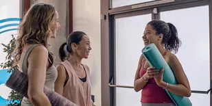 People holding yoga mats talking in entryway